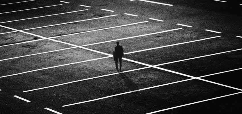 Person standing alone in a dark parking lot.