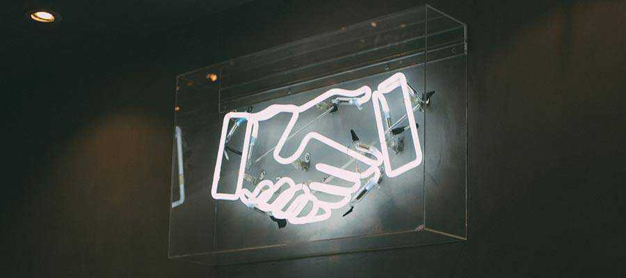 A neon sign depicting a handshake.